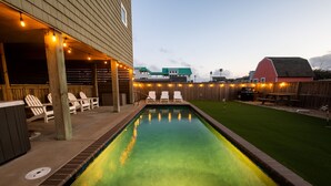 A swimming pool with a wooden deck and lounge chairs, surrounded by a wooden fence and a grassy lawn. - Steps to the Sand-Ocean Views-Hot Tub/Heated Pool-Putting Green-Coffee Bar (Kitty Hawk)