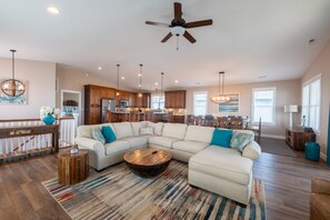 A spacious living room with a large sectional sofa, a wooden coffee table, and a ceiling fan.