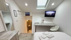 A modern hotel room with a large bed, a bathroom with a sink and mirror, a TV mounted on the wall, and a skylight above the bed. - Ze Perfect Place - Opera Nice - Apartment 2 Bdrms - AC - Terrace (Nice)