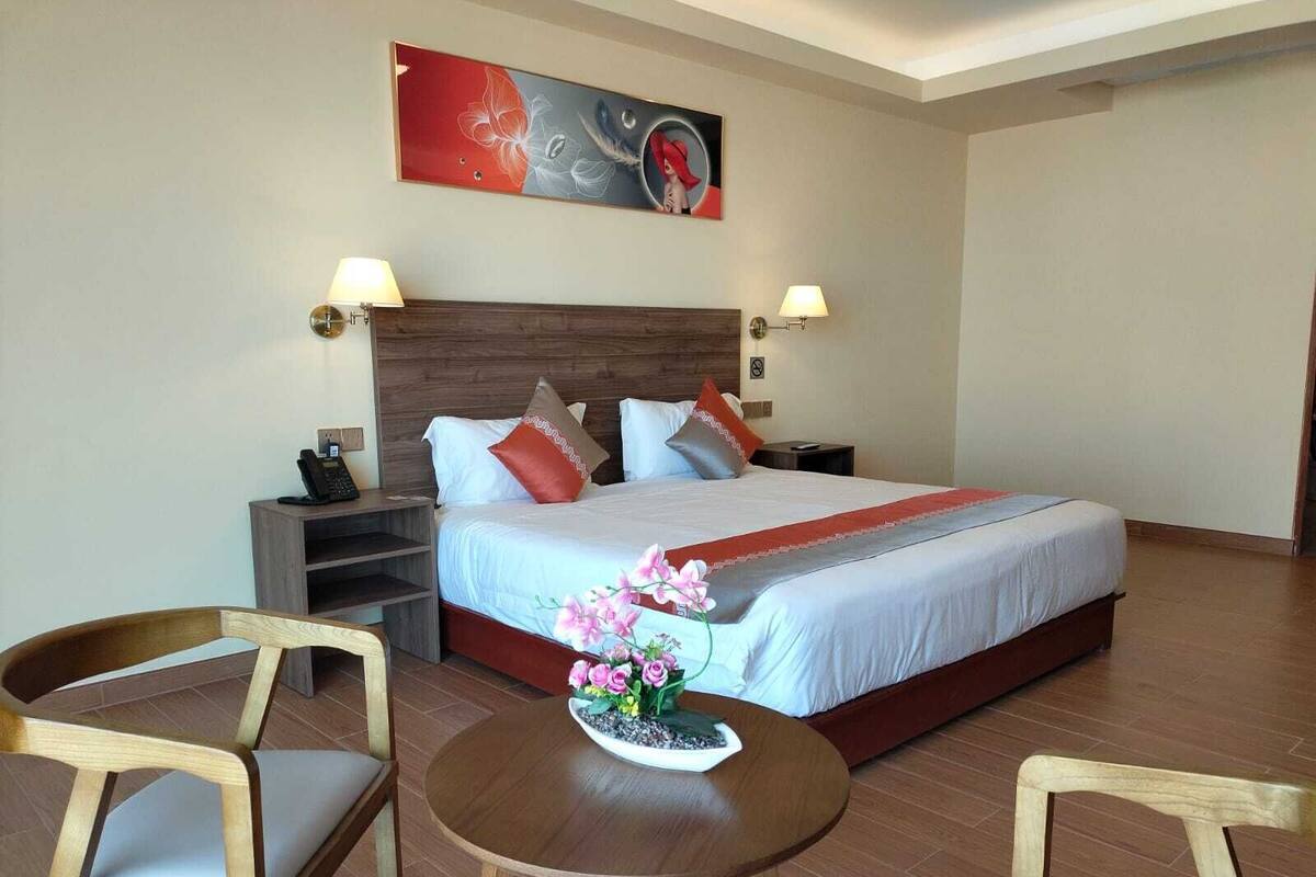 Una habitación de hotel con una cama grande, dos mesitas de noche, un escritorio y dos sillas.