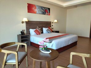 Een hotelkamer met een groot bed, twee nachtkastjes, een bureau en twee stoelen.