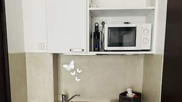 Una kitchenette compacta con microondas, pileta y heladera pequeña.