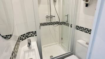 A modern bathroom with a glass-enclosed shower, a white sink, and a toilet.