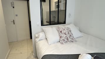 Une chambre d’hôtel avec un lit, un miroir, une armoire et une salle de bain visible à travers la porte.