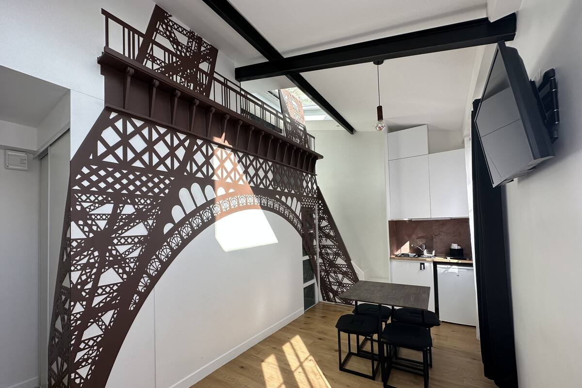A modern interior with a wooden staircase, a dining area with a table and chairs, and a kitchen with cabinets and a sink.