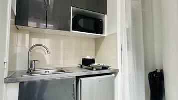 A compact kitchen with a refrigerator, a microwave, and a sink.