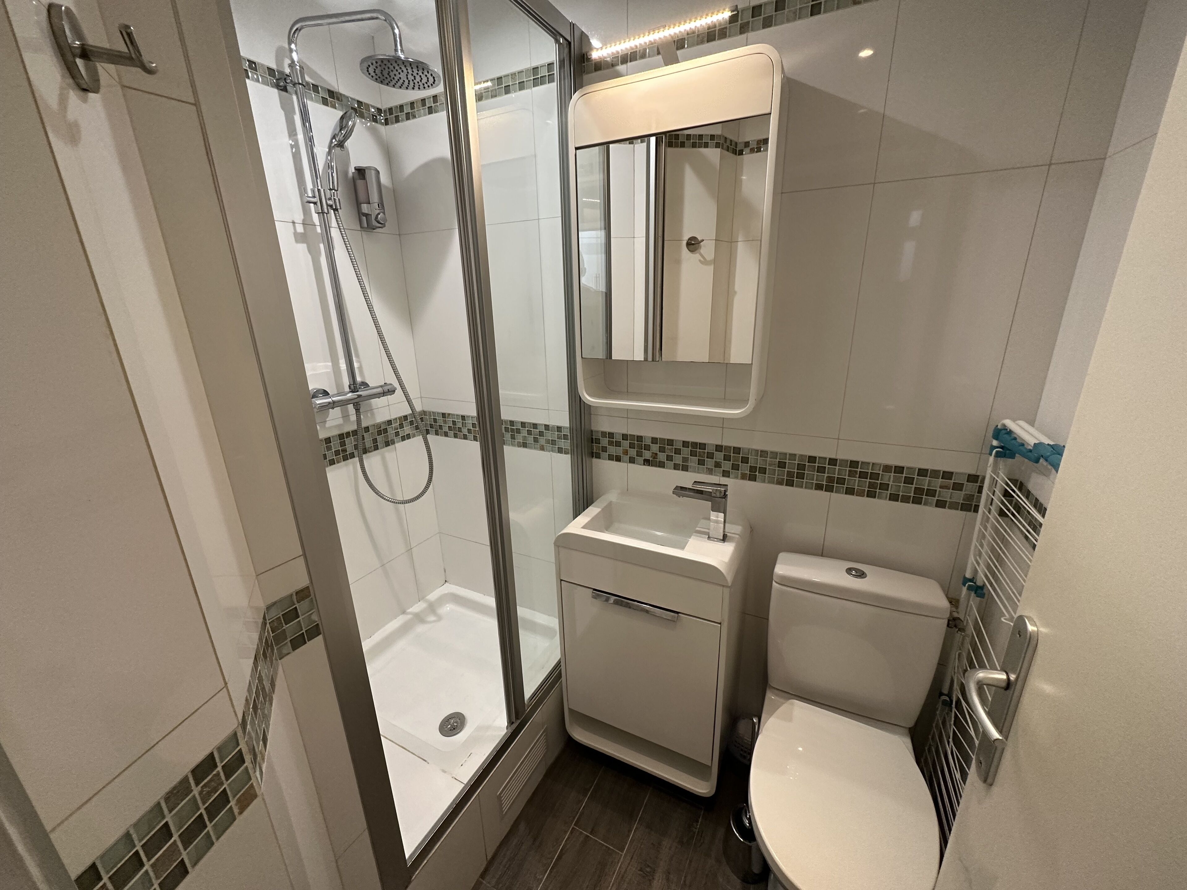Een moderne badkamer met een douchecabine van glas, een wit wastafelmeubel en een toilet.