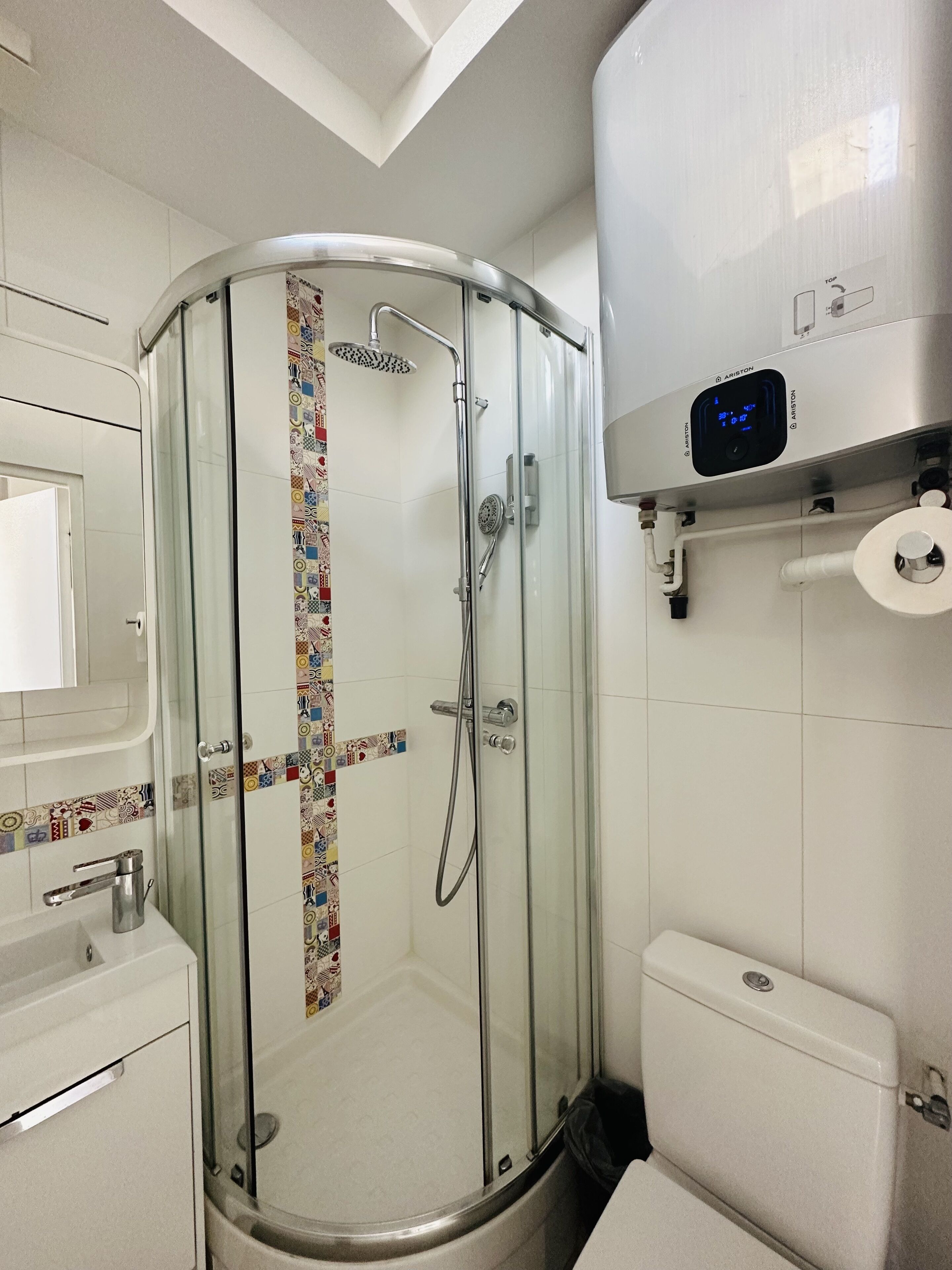 Een moderne badkamer met een douche met glazen wand, een toilet en een wastafel.