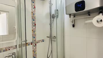 Un baño moderno con ducha de mampara de vidrio, inodoro y lavamanos.