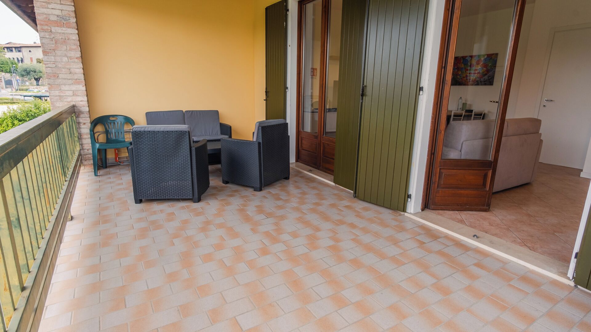 A balcony with a tiled floor, a table with chairs, and a sliding glass door leading to an interior room.