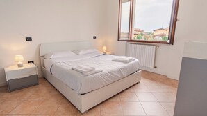 Quarto com uma cama, mesas de cabeceira, uma janela e um radiador.