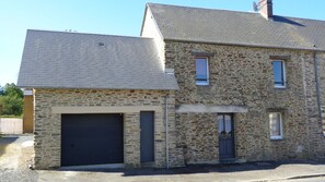 A two-story stone building with a garage, a small porch, and a satellite dish. - Le Courtil 3* (Cerisy-la-Forêt)