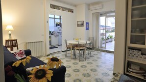A living room with a sofa, a dining table with chairs, a lamp, and sunflowers. - An apartment nestled in the sun 110 meters from the sea (Scauri)