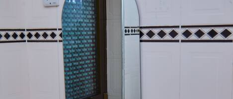 Baño con lavamanos blanco, espejo y pared de azulejos.