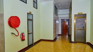 Un passadís amb un extintor, un rètol de restaurant i un ascensor.