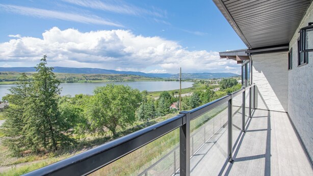 A balcony with a view of a lake, trees, and distant mountains. - Newly renovated with Lakeviews, big yard, minutes to Silver Star/Golf/Wineries. (Vernon)