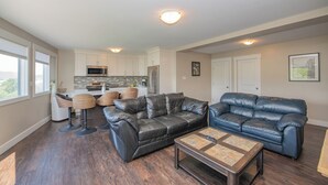 A modern living room with leather sofas, a coffee table, and a kitchen in the background. - Newly renovated with Lakeviews, big yard, minutes to Silver Star/Golf/Wineries. (Vernon)