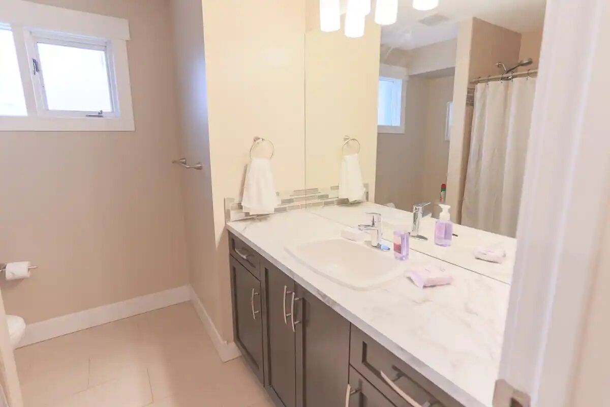A bathroom with a large mirror, a sink, and a shower curtain.