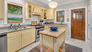 Une cuisine avec des meubles de couleur claire, un îlot central, une cuisinière et un évier.