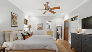 Une chambre à coucher avec un lit, un ventilateur de plafond, une commode et un miroir.