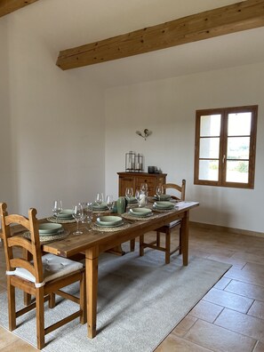 A dining area with a wooden table set for six, surrounded by wooden chairs with cushioned seats.