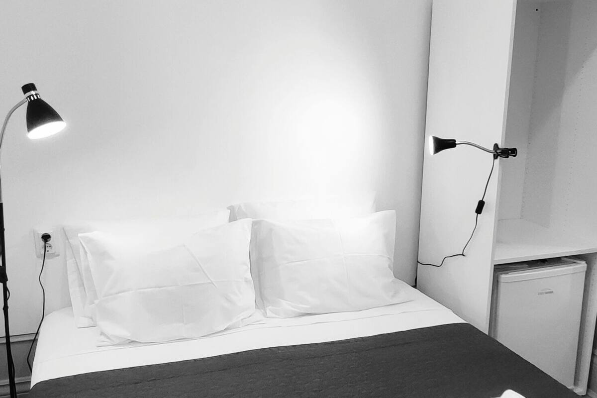 Een hotelkamer met een bed, een bedlampje, een kast en een kleine koelkast.