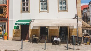 A two-story building with a white facade, multiple windows, and a covered outdoor seating area. - Vila Santa Cruz Guest House (Braga)