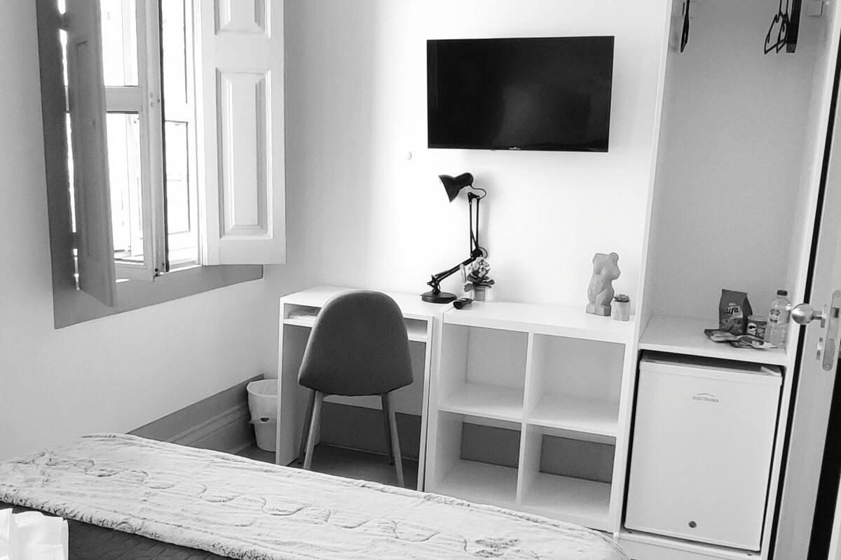 Een kleine hotelkamer met een bed, een bureau, een stoel, een televisie en een kledingkast.