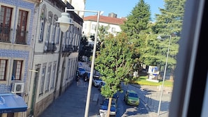 Eine Kopfsteinpflasterstraße mit geparkten Autos und einem Gebäude mit blau-weißen Fassaden.