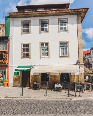 Un bâtiment à deux étages, doté d’une façade blanche, de nombreuses fenêtres et d’un espace extérieur aménagé avec des sièges.