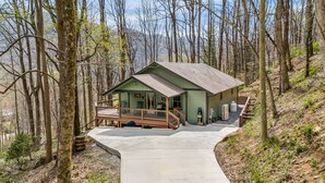 A small cabin with a porch, surrounded by trees.