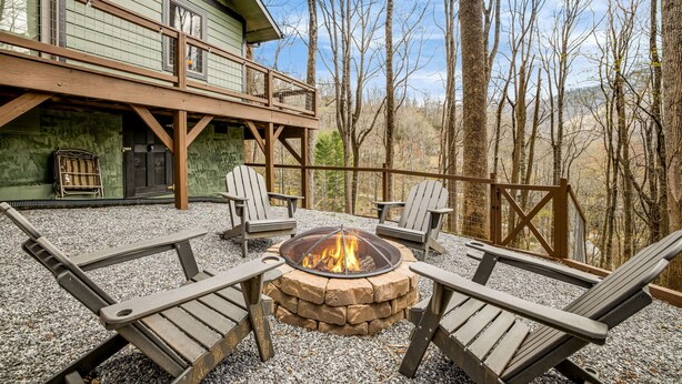 A wooden deck with Adirondack chairs and a stone fire pit.