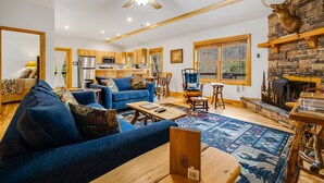 A spacious living area with a blue sofa, wooden coffee table, and a fireplace with antlers.