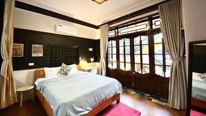 Ein Schlafzimmer mit einem Bett, einem Nachttisch, einem Sessel, einem Fenster mit Vorhängen und einer Deckenleuchte.