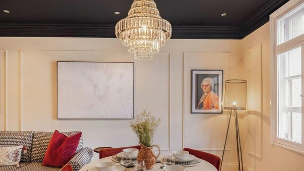 A dining area with a chandelier, a table set for four, and a framed picture on the wall.