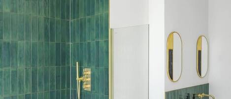 Un baño con ducha, dos espejos, lavamanos e inodoro.