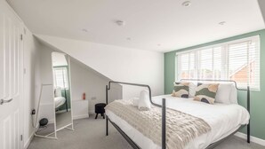 Une chambre avec un lit superposé, un grand miroir, un petit tabouret et une fenêtre avec des stores.