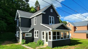 A two-story house with a dark exterior, white trim, and a covered porch.
