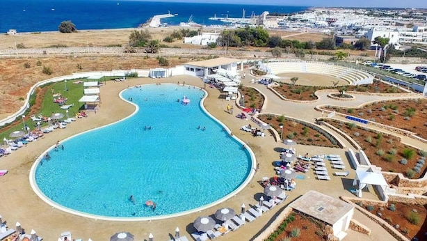 An aerial view of a resort with a large central swimming pool, sun loungers, and a scenic ocean view. - Holiday Apartment "Villa Katia - Villanova di Ostuni" with Private Terrace and Wi-Fi (Villanova di Ostuni)