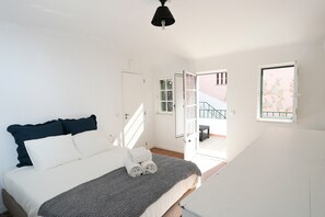 Makuuhuone, jossa on sänky, ikkuna ja ovi, joka johtaa parvekkeelle.