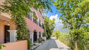 A narrow cobblestone street flanked by buildings with balconies and a tree-lined path. - Apartment "Apollon" with Sea View, Garden & Wi-Fi (Lefkada)