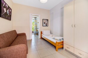 A bedroom with a bed, a sofa, a wardrobe, and a door leading to a balcony.