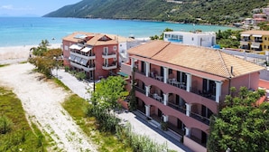 A coastal hotel with multiple balconies, a beach, and a mountainous backdrop. - Apartment "Apollon" with Sea View, Garden & Wi-Fi (Lefkada)