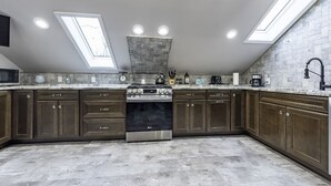 Une cuisine moderne avec des meubles en bois foncé, une cuisinière en acier inoxydable et un puits de lumière.