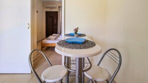 Un petit coin repas avec une table ronde, deux chaises et un vase décoratif.