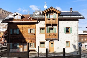 Un bâtiment à deux étages doté d’une façade en bois, d’un balcon et d’un panneau solaire sur le toit.