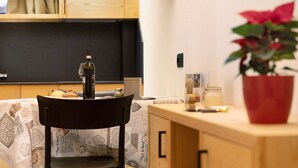 A dining area with a table set for two, a chair, a bottle of wine, and a potted plant. - Apartment "Stelo Rosina's Home" (Livigno)