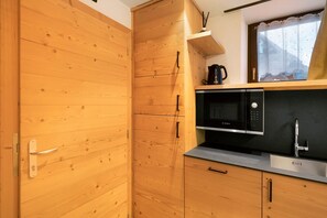 Una cocina compacta con armarios de madera, un microondas Bosch y un lavamanos.