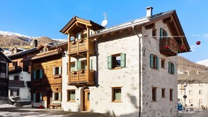 A traditional chalet with wooden balconies, a stone facade, and a mountainous backdrop. - Apartment "Stelo Rosina's Home" (Livigno)