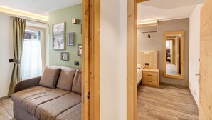 Una stanza con pavimento in legno, un divano, un letto, uno specchio e quadri appesi al muro.